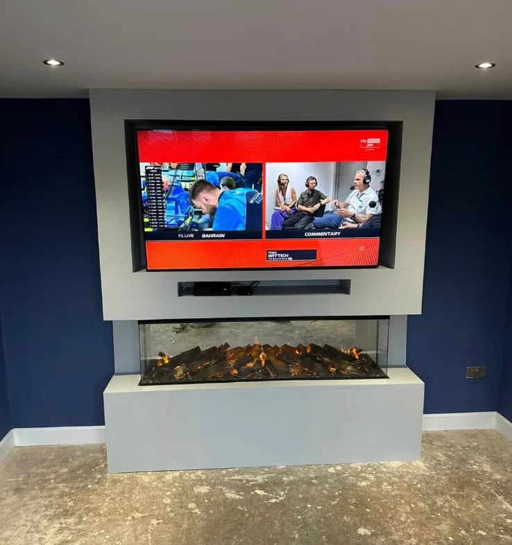 A media wall with a British Fires New Forest 1600 Deluxe fire and a recessed television on a deep navy wall in Castle Bromwich