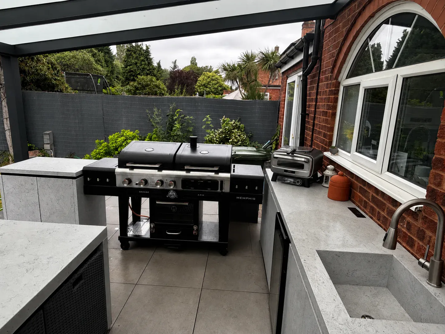 A bespoke outdoor kitchen with an integrated sink under a veranda in Castle Bromwich