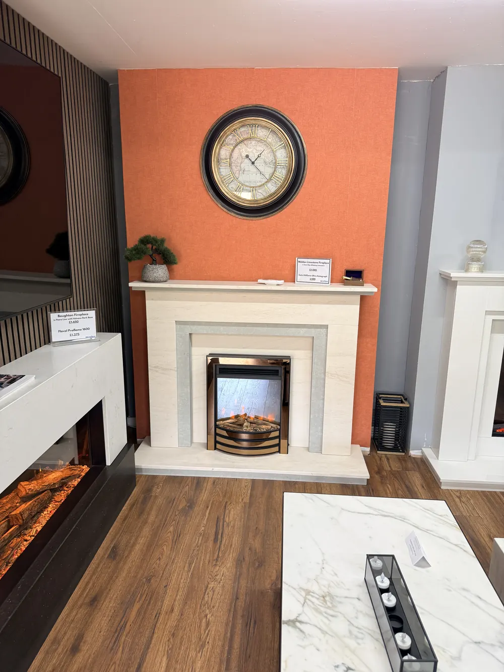 A limestone fireplace surround with an inset electric fire against a burnt orange feature wall