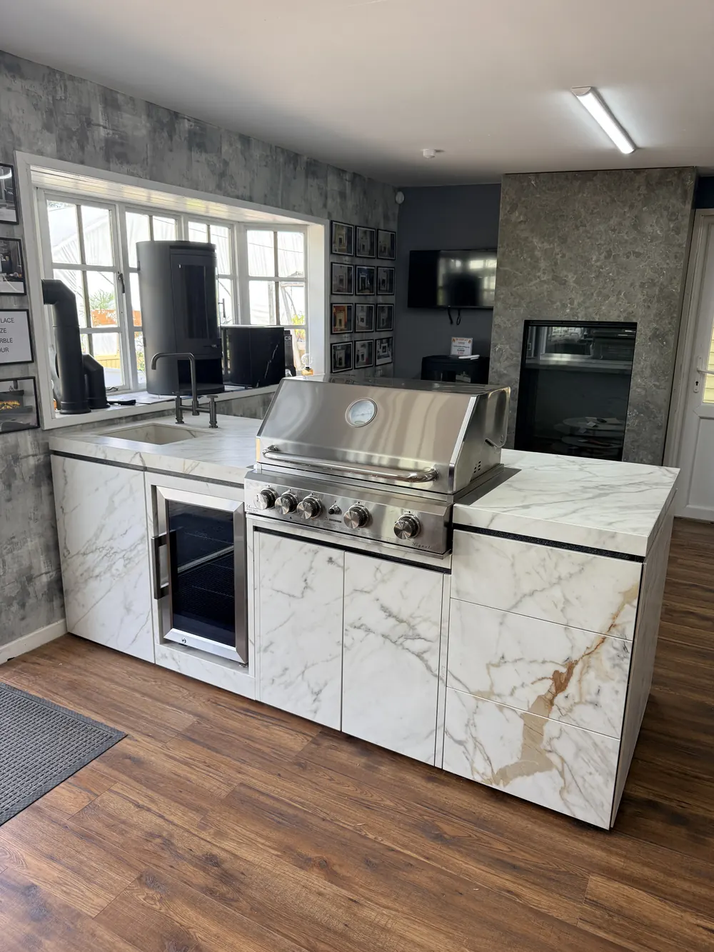 A bespoke outdoor kitchen display with a built-in barbecue, drinks fridge and porcelain worktop